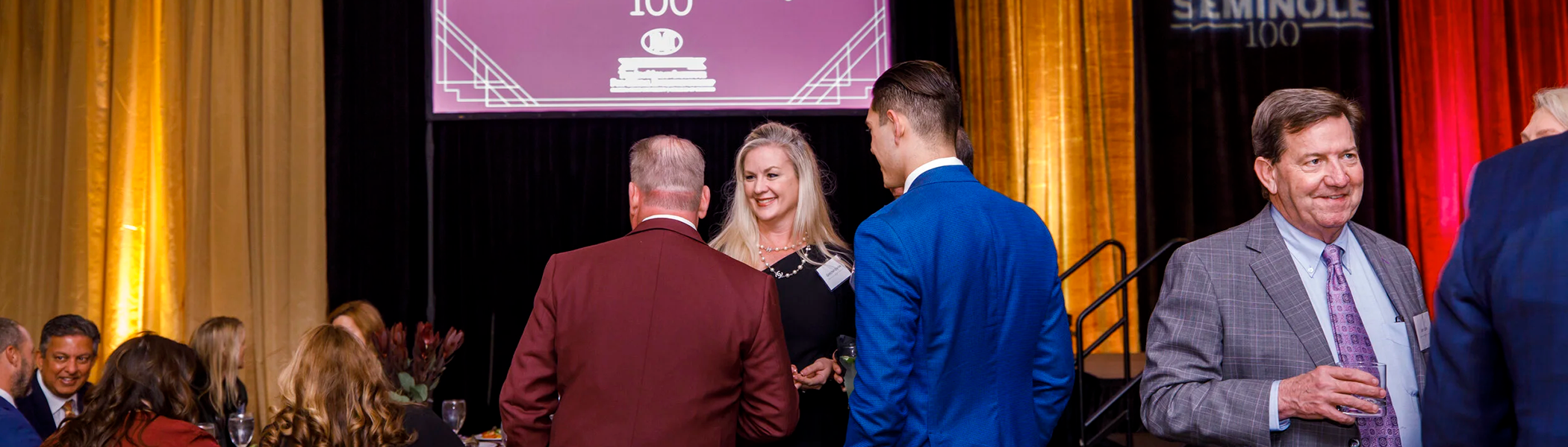 A photo centered on three people mingling at the Seminole 100 award ceremony